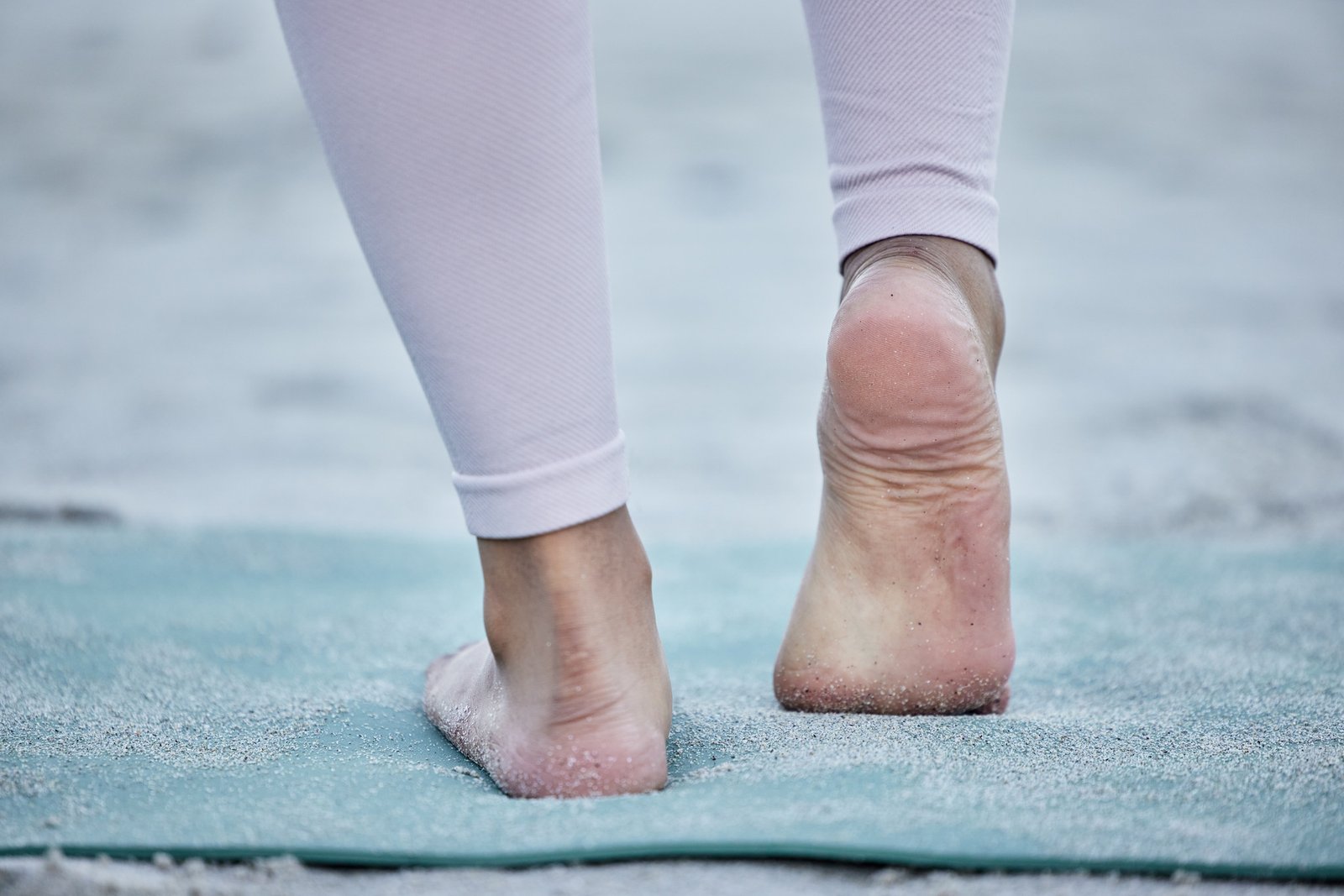 Bare feet standing on an exercise mat, showing the heels and arches